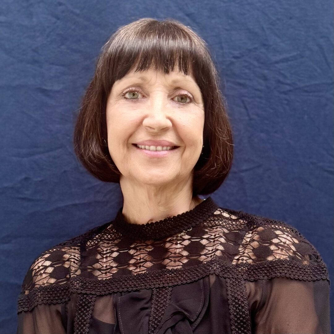 A woman with short hair and bangs wearing a black dress.